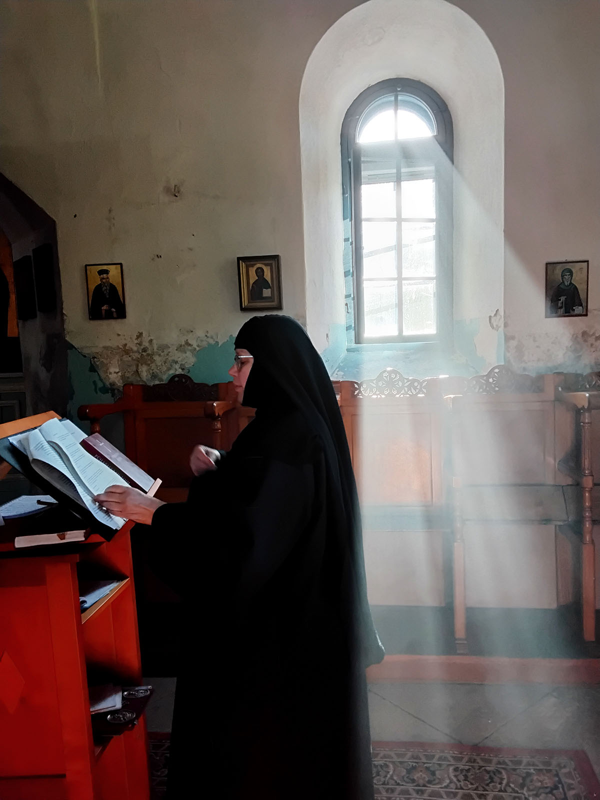 Nunna rukoilee analogin äärellä. Ikkunasta tulvii sisään valonsäteitä.